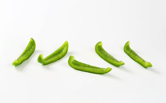 Thin slices of fresh green pepper on white background