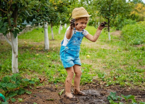 a child in the dirt in the garden holds the soil in his hands. Selective focus. Kid.