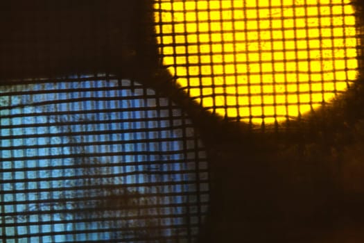 abstraction of lights behind metal mesh low light
