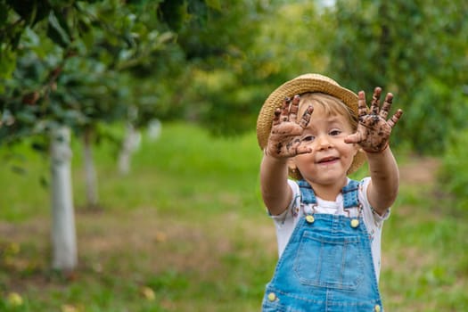 a child in the dirt in the garden holds the soil in his hands. Selective focus. Kid.