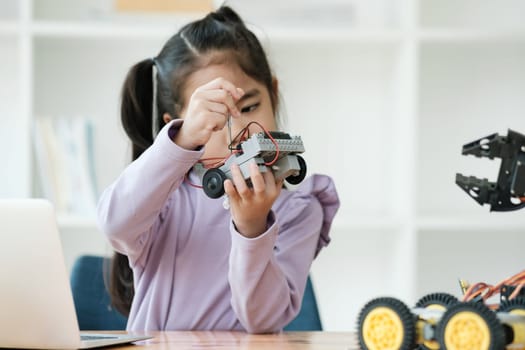 Asian girl concentrating on building a robot, embodying STEM education.