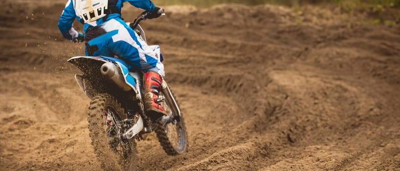 Moto cross - MX girl biker at race in Russia - a sharp turn and the spray of dirt, rear view - close up, telephoto