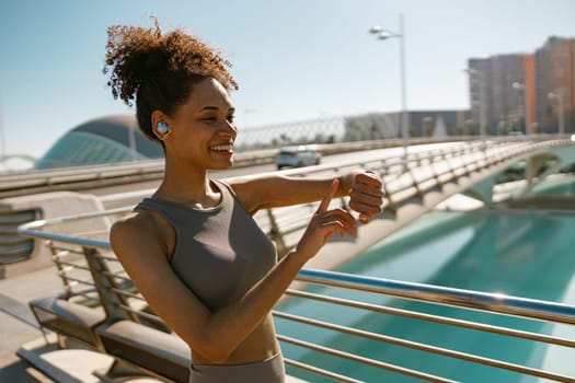 Young fit woman looking at smartwatch and counting calories burned. Healthy life concept