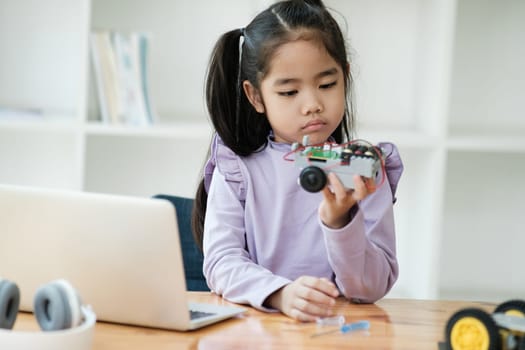 Asian girl concentrating on building a robot, embodying STEM education.