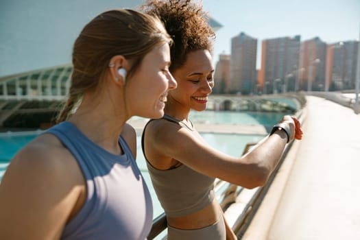 Young fit woman looking at smartwatch and counting calories burned. Healthy life concept