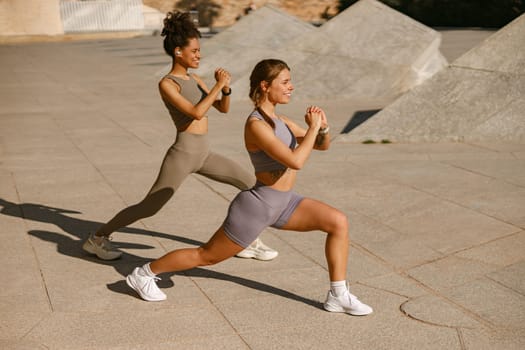 Athletic women in sportswear are stretching legs before doing workout outside in morning