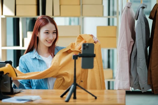 Woman with a social media influence is greeting the audience for recording vlog video live streaming, Lift the postage box during the live show to confirm the customer's order, Online fashion clothing