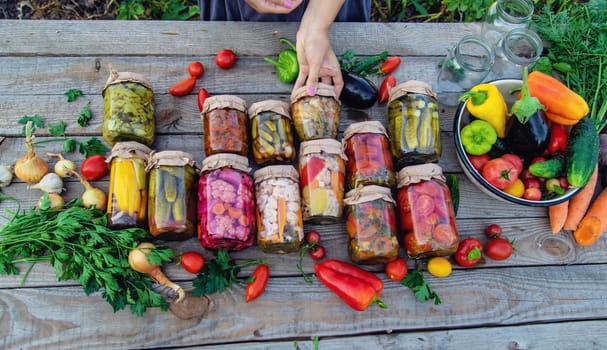 Woman canning vegetables in jars on the background of nature. preparations for the winter.