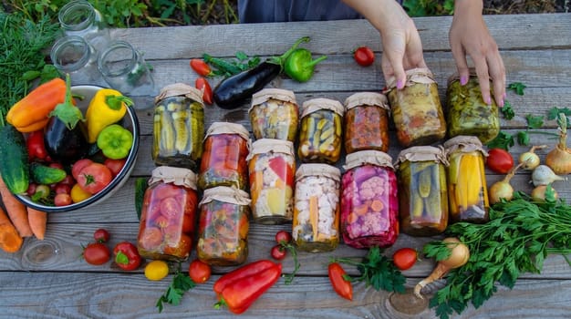 Woman canning vegetables in jars on the background of nature. preparations for the winter.