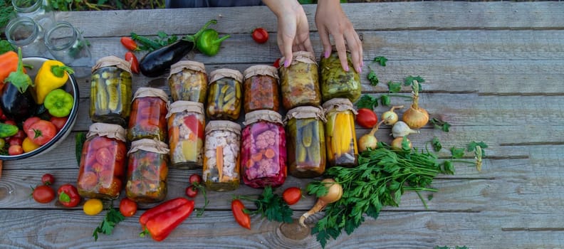 Woman canning vegetables in jars on the background of nature. preparations for the winter.