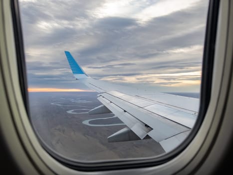 Sunset and airplane wing view from flight window.