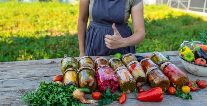 Woman canning vegetables in jars on the background of nature. preparations for the winter.