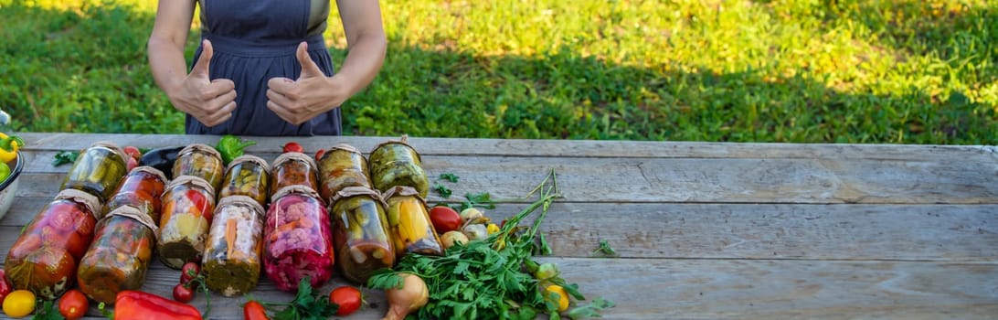 Woman canning vegetables in jars on the background of nature. preparations for the winter.