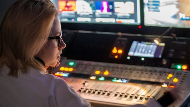 Russia October 2020. the girl sound engineer works works on the broadcast at the sound console. low light