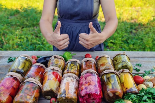 Woman canning vegetables in jars on the background of nature. preparations for the winter.