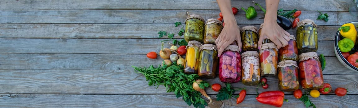 Woman canning vegetables in jars on the background of nature. preparations for the winter.