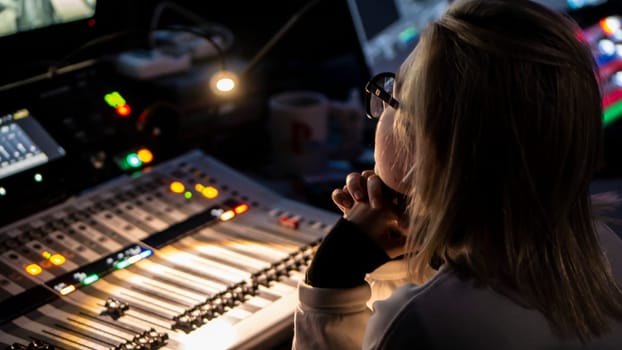 Russia October 2020. the girl sound engineer works works on the broadcast at the sound console. low light
