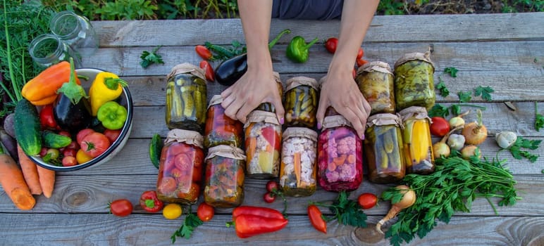 Woman canning vegetables in jars on the background of nature. preparations for the winter.