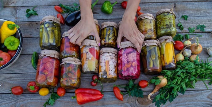 Woman canning vegetables in jars on the background of nature. preparations for the winter.