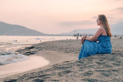 Woman sits on the beach and looks at the sea in Alanya city, Turkey. Travelling or vacation concept