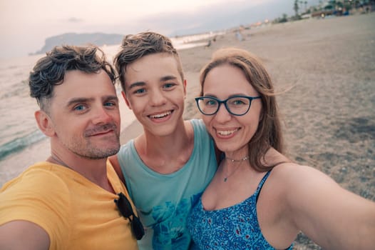 Happy family taking a photo on a beach at the sea in Alanya city, Turkey. Travelling or vacation concept