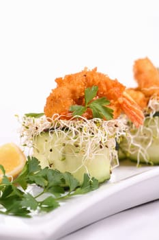 Cucumber appetizer with fried breaded shrimp on a bed of microgreens