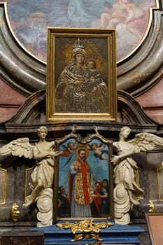 Poznan, Poland - June 18, 2023: A painting is displayed on the wall above a statue of an angel. The angel statue stands beneath the artwork, creating an impactful visual composition.