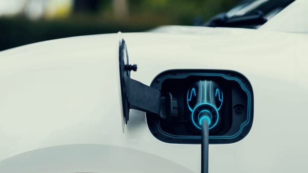 Front view EV charger plugged into electric car for electric recharging from electric charging station with glowing light cable. Cutting-Edge innovation and future green energy sustainability. Peruse