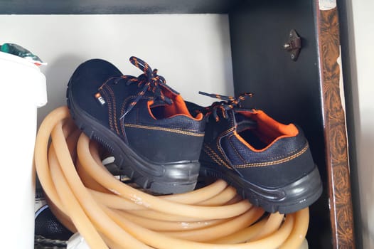A Pair of Boots Resting on Coiled Orange Hose Inside a Cabinet