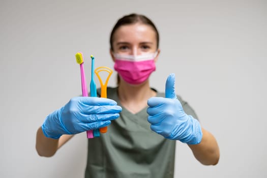 Dentist holding toothbrushes and shows thumb up.