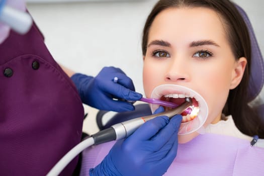 Young beautiful woman undergoes tooth filling in dentists office