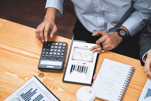 Top view multiracial analyst team use BI dashboard data to analyze financial report on meeting table. Group of diverse business people utilize data analysis by FIntech for business decision. Concord