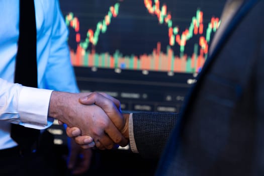 Investor stock trading of business partners shaking hands against screen for cooperating of investing agreement of highest valued technology product trending on the dynamic market stock. Sellable.