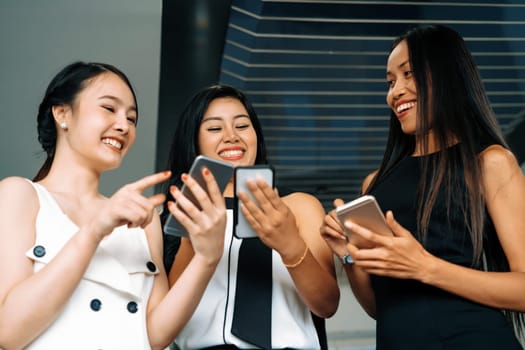 Three women friends having conversation while looking at mobile phone in their hands. Concept of social media, gossip news and online shopping. uds