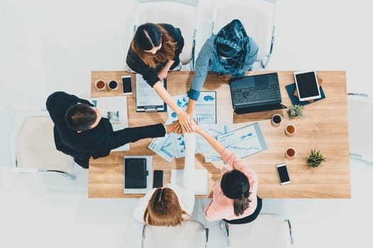 Businessmen and businesswomen joining hands in group meeting at multicultural office room showing teamwork, support and unity in business. Diversity workplace and corporate people working concept. uds