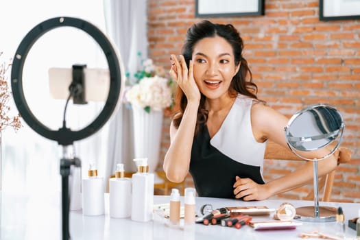 Woman influencer shoot live streaming vlog video review makeup uttermost social media or blog. Happy young girl with cosmetics studio lighting for marketing recording session broadcasting online.