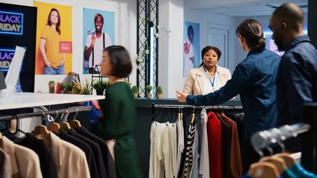 Happy customer at checkout counter in retail store, buying new clothes during black friday event. Young man carrying stander full of clothing items and accessories, seasonal sales obsession.