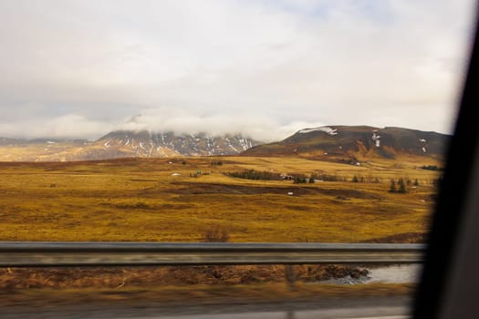 Roadtrip landscapes in iceland with scandinavian countryside life and spectacular scenic roads. Car drive sightseeing icelandic nature with frozen fields and mountain hills, northern cityscape.