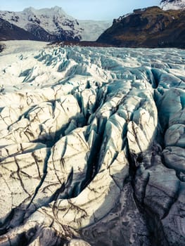 Fantastic vatnajokull glacier in iceland surrounded by freezing cold water and rocky icy hills, icelandic nordic scenery. Massive blue transparent icebergs with frosty rocks and cracks.