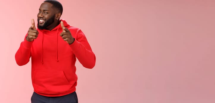 Nice work well done friend. Proud cheering good-looking cheeky young flirty black guy beard in red hoodie pointing finger pistols camera smug congratulating mate good game, standing pink background.