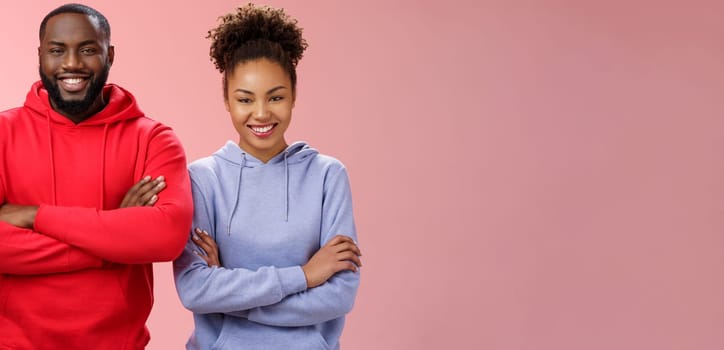 Charming happy professional team two african american man girl smiling broadly self-assured own abilities cross arms chest grinning friendly unbeatable working together, standing pink background.