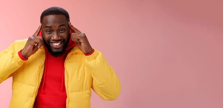 Think about it. Portrait charming creative young happy african guy bearded hold index fingers temples brain smiling broadly share awesome idea great thought, grinning silly standing pink background.