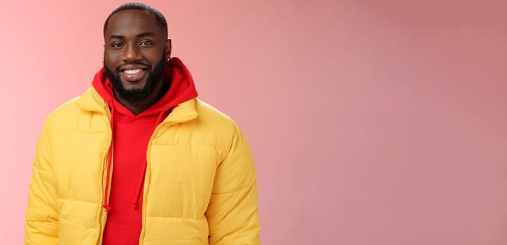 Waist-up happy charismatic good-looking bearded guy in yellow jacket red hoodie smiling joyfully white perfect smile talking have nice friendly conversation, standing pink background.