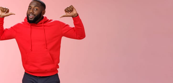 Proud confident arrogant good-looking african american bearded male coworker in red hoodie raise thumbs pointing himself bragging look cheeky talking accomplishments himself, standing pink wall.