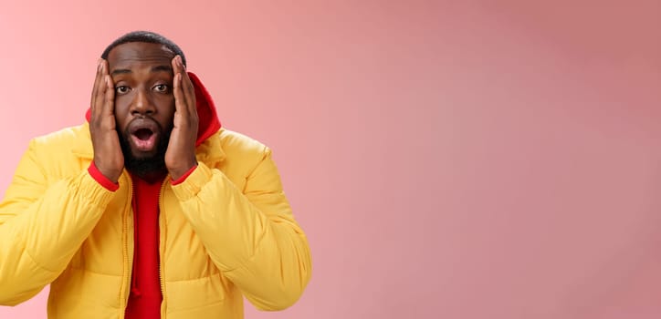 Shocked amazed impressed handsome african bearded guy drop jaw gasping astonished press palms cheeks witness surprising unexpected event, standing speechless stupor pink background. Copy space