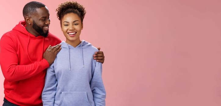 Supportive boyfriend congratulating girlfriend win first prize feel proud touching girl shoulder saying encouraging pleasant words smiling look caring lovely grinning, standing pink background.