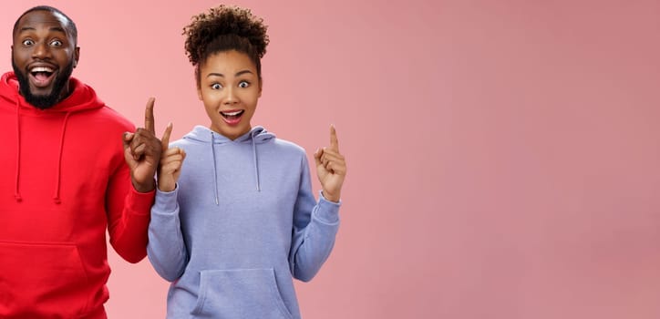 Lifestyle. Amused charismatic two best friends african american brother sister pointing raised index fingers up widen eyes imressed amused feel happy go study abroad together winning trip standing surprised.