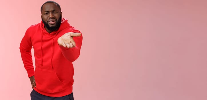 Displeased african-american man scolding friend acting bad asking what doing life pointing camera palm arguing standing disappointed judging mate outfit, standing pink background. Copy space