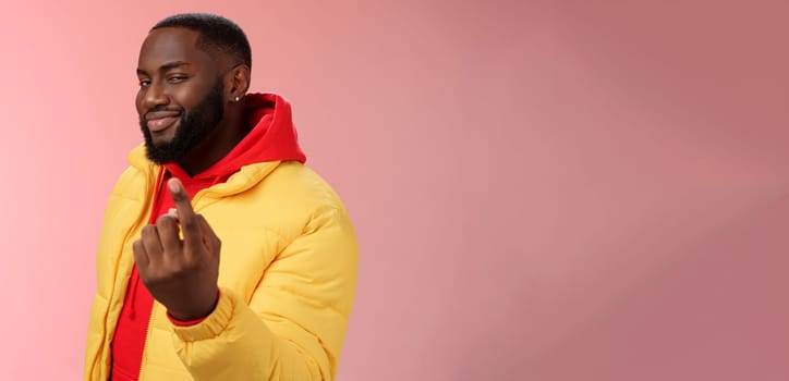 Cheeky flirty black bearded guy asking come closer beckon index finger camera smiling make smug face have plans for you alluring join, standing pink background devious grin. Emotions concept