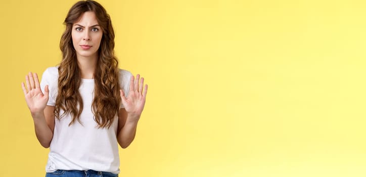 No thats enough. Serious-looking confident woman restrain man demand stay away give refusal look intense prohibit rejecting suspicious unpleasant offer stand yellow background. Copy space